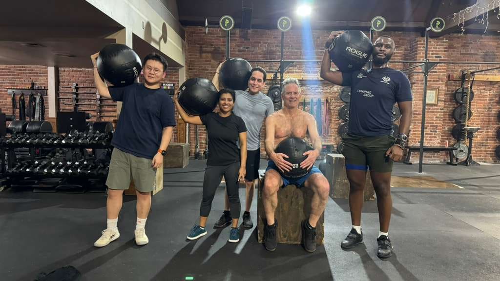 Corporate group class members posing with wall balls at Persistence Athletics, Belltown Seattle