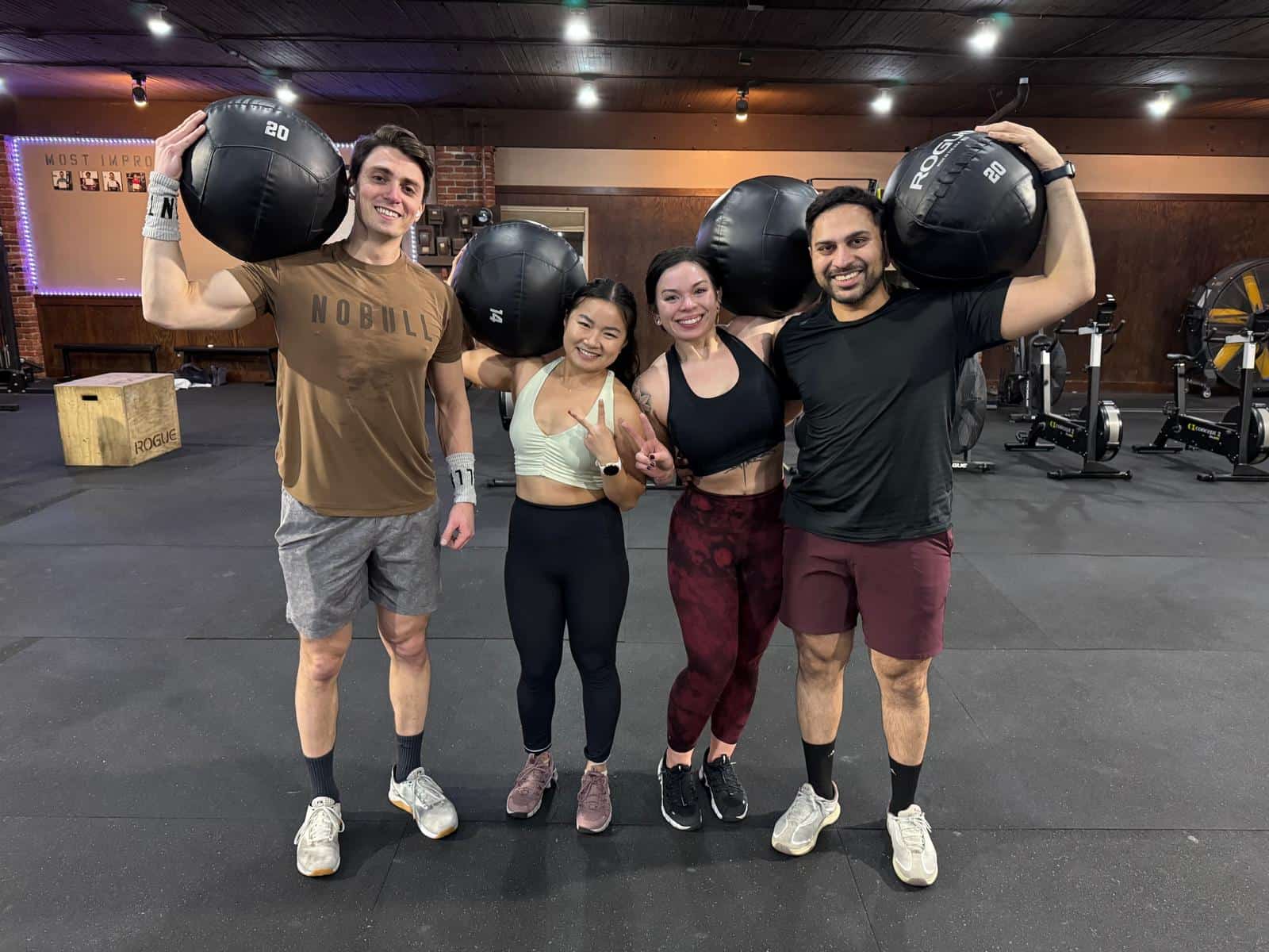 Four Persistence Athletics members posing with wall balls after class, Belltown Seattle