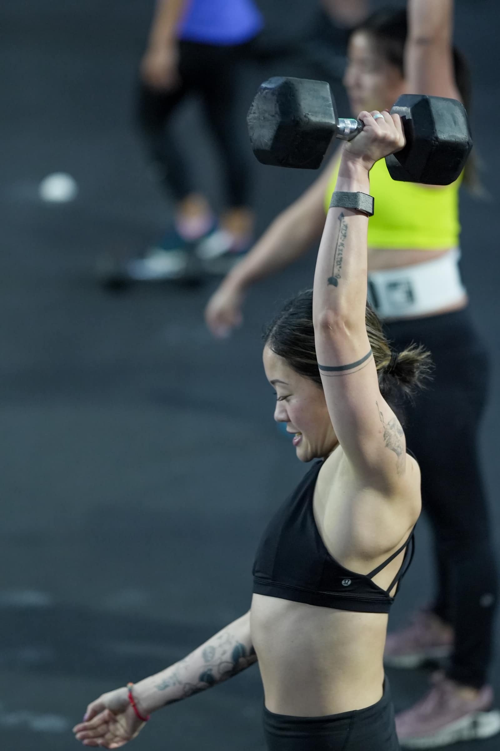 Member finishing an overhead dumbbell press at Persistence Athletics, Belltown Seattle